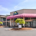 Exterior of the Days Inn in Princeton, featuring a two-story building with a large red awning over the entrance, landscaping, and a signature Days Inn sun logo sign.