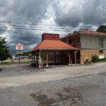 Economy Inn with a red roof and covered entrance, located near a roadside sign under a cloudy sky.