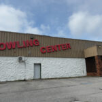 Exterior of Green Valley Bowling Center with bold red letters on a tan and white building, set against a cloudy sky.