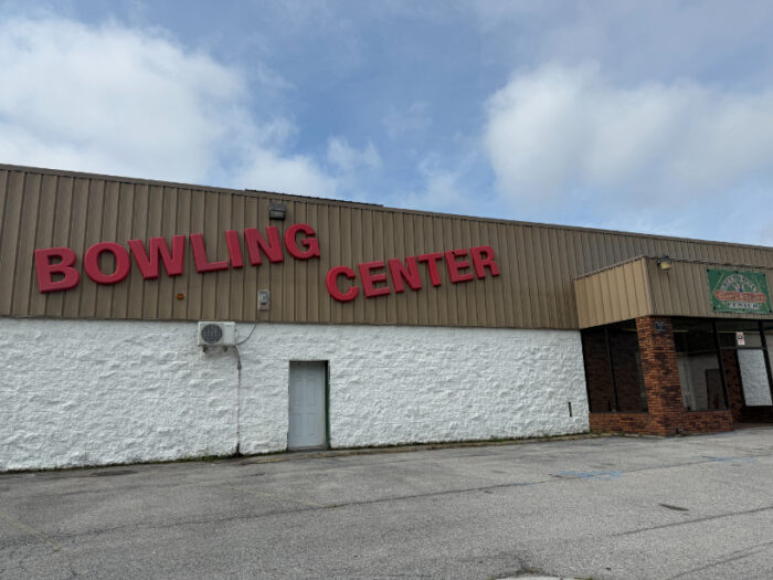 Exterior of Green Valley Bowling Center with bold red letters on a tan and white building, set against a cloudy sky.
