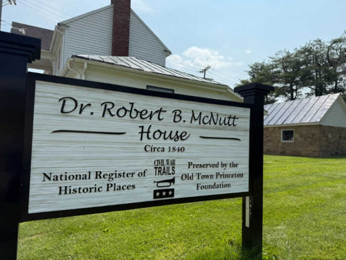 Sign for the Dr. Robert B. McNutt House, a historic 1840s home with light siding and a red brick chimney.