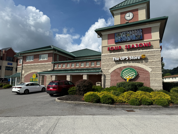 The Willow Gift Gallery in a large brick and tan building with a green roof, windows, and a corner tower featuring a clock. A UPS Store sign is also mounted on the tower.