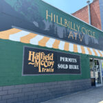 Hillbilly Cycle ATV storefront with a green and yellow striped mural advertising Hatfield-McCoy Trail permits.