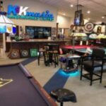 Interior of K&K Music with pool tables, WVU-themed decor, bar seating, and vintage signs and instruments on display.