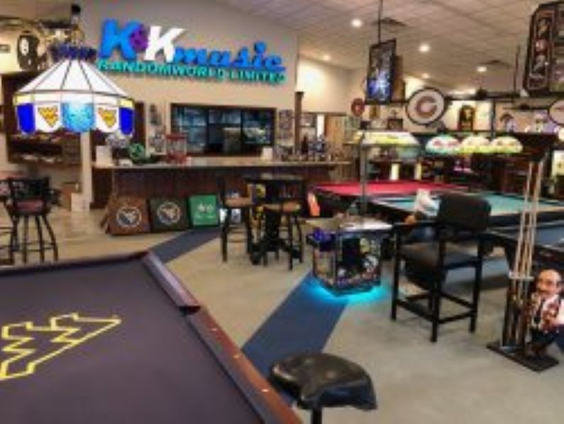 Interior of K&K Music with pool tables, WVU-themed decor, bar seating, and vintage signs and instruments on display.