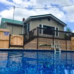 Four Wheeler Heaven lodging with a raised wooden deck and above-ground pool, set against a partly cloudy sky.