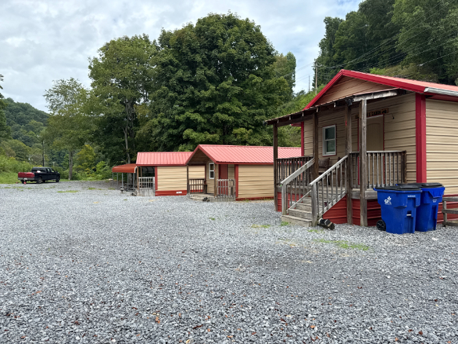 Gravel lot with several small tan cabins with red trim and metal roofs, known as Crane Creek Cabins.