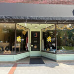Honeycomb Cafe storefront with large display windows decorated with bees and honeycomb designs, and an 'Open' sign hanging inside.