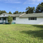 Ashland Retreat, a white single-story house with a large grassy lawn and trees in the background.