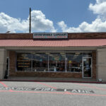 Front view of Stoneworks Lapidary, a storefront with large display windows featuring crystals and fossils, and a sign above reading 'Stoneworks Lapidary: Crystals, Fossils, Jewelry.'