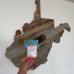 A tea in front of a WV wooden wall decoration.