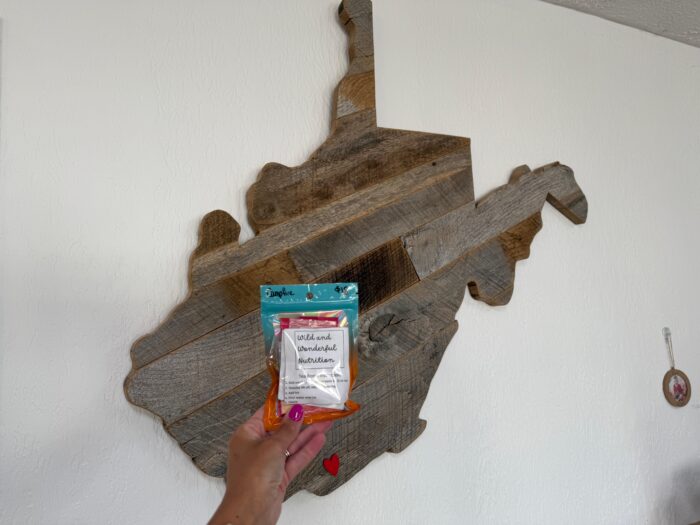 A tea in front of a WV wooden wall decoration.