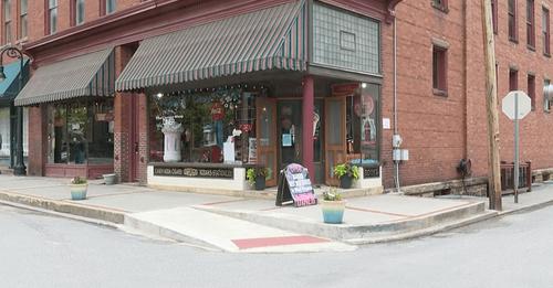 Corner view of Corner Suites, a red brick building with striped awnings and decorative storefront windows, located at a downtown intersection.