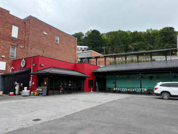 Casa Familia Restaurant exterior with a bright red front section attached to a larger brick building, black awnings, and a green outdoor dining area.