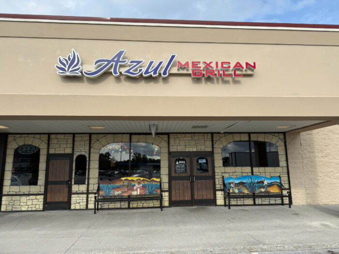 Front of Azul Mexican Grill with stone facade, large windows, colorful painted benches, and a sign above the entrance.