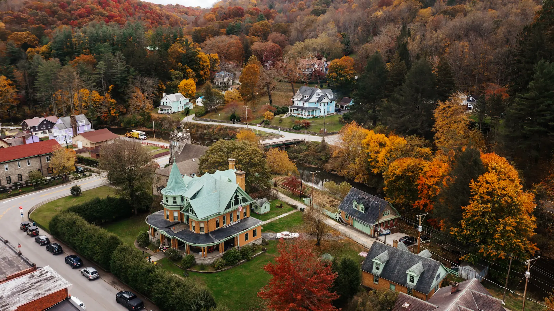 Aerial view of Bramwell, WV, in Mercer County during peak fall foliage, showcasing historic Victorian homes surrounded by vibrant autumn colors nestled in the Appalachian hills.