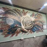 Colorful abstract mural inside Mad Mud Studios LLC featuring bold red, blue, black, and white brushstrokes surrounding a circular “Mad Mud Studios LLC” logo, painted on a light green interior wall