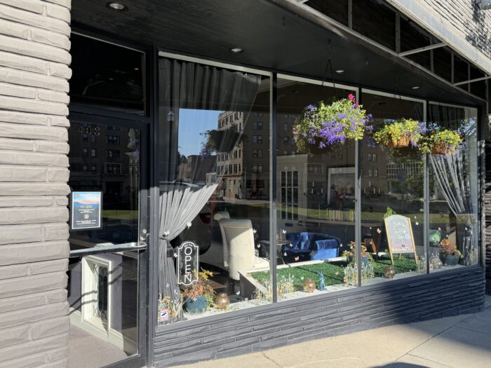 Exterior of Bella’s Tea Room and Coffee Shop in downtown Bluefield, West Virginia, featuring large front windows, hanging flower baskets, outdoor decor, and a cozy seating area inside the storefront.