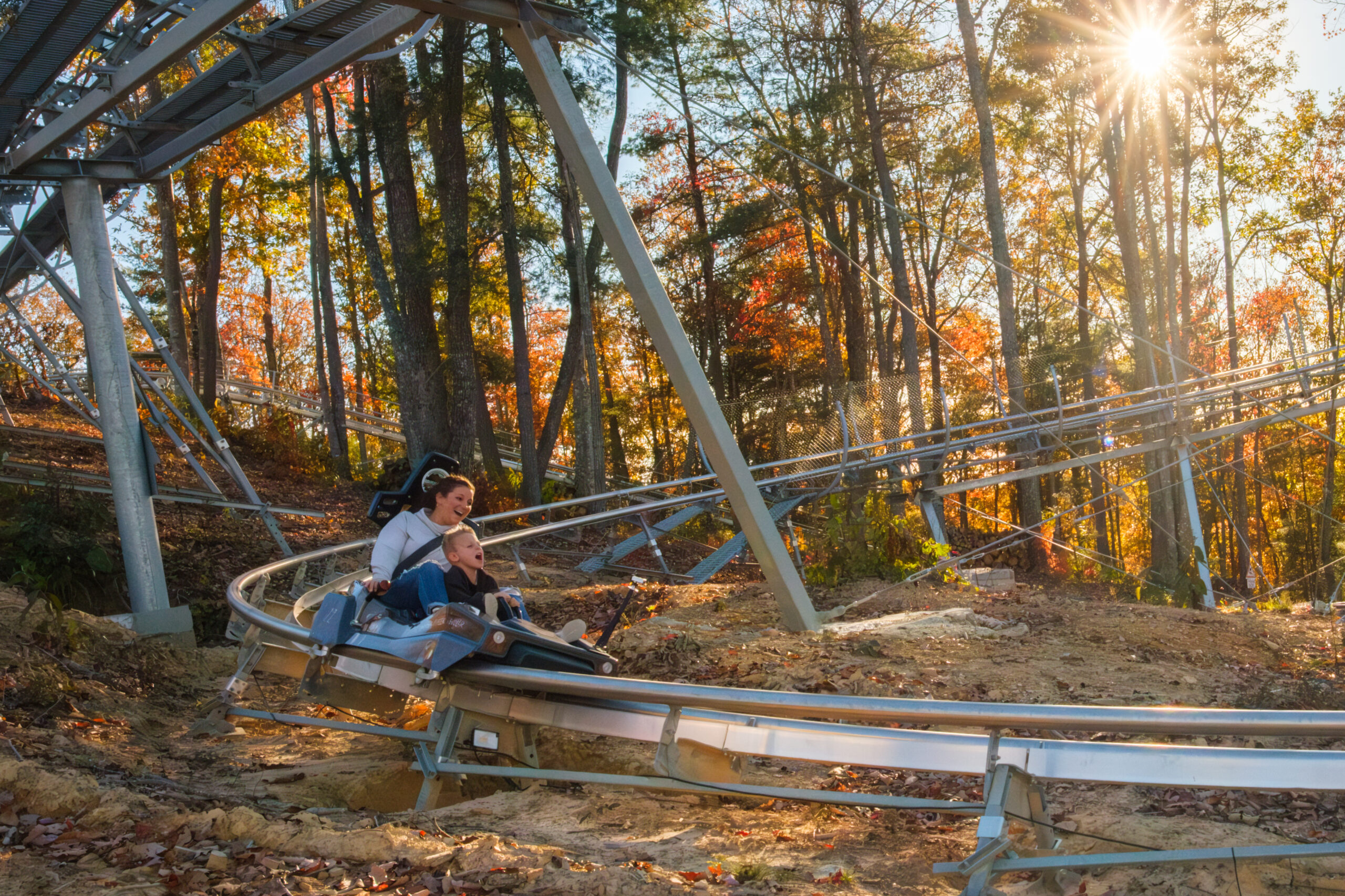 A mother and child ride the Brush Creek Holl’r Mountain Coaster through colorful fall woods in Mercer County, West Virginia.