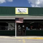 : Exterior of The Robin’s Nest Furniture & Finds in Bluewell, West Virginia, with a green storefront, business sign and American flag.