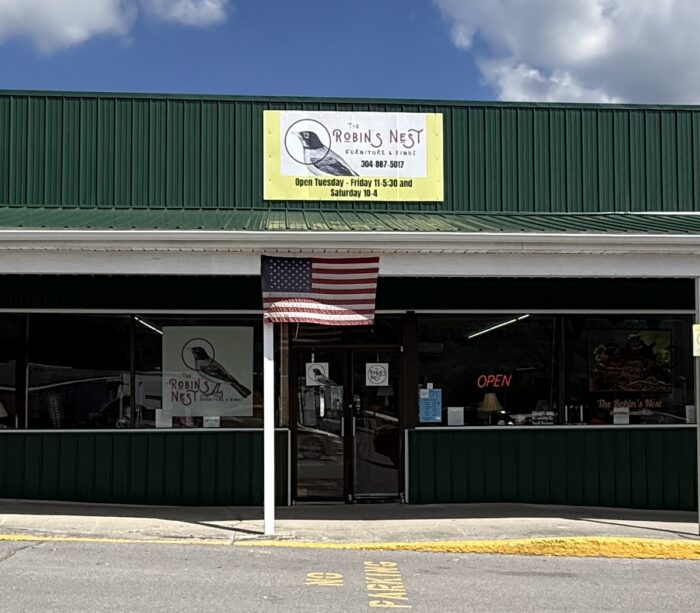 : Exterior of The Robin’s Nest Furniture & Finds in Bluewell, West Virginia, with a green storefront, business sign and American flag.